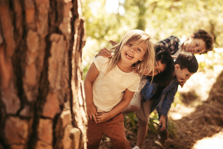 Fröhliche Kinder spielen im Wald und haben Spaß