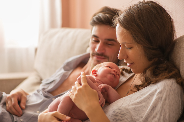 Stolze Eltern haben Kuschelzeit mit neugeborenem Baby